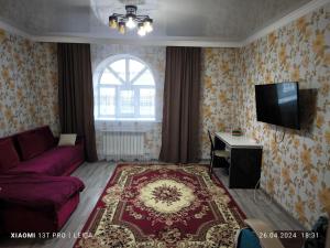 sala de estar con sofá rojo y TV en Уютная квартира комфорт класса74, en Astana