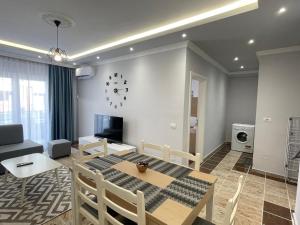 a living room with a table and chairs and a clock at Fishta Quality Apartments Q5 31 in Velipojë