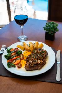 a plate of meat and vegetables with a glass of wine at Foz Plaza Hotel in Foz do Iguaçu