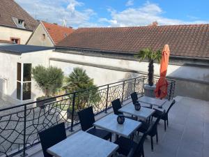 eine Terrasse mit Tischen, Stühlen und einem Sonnenschirm in der Unterkunft Champagne Domaine Sacret - AY in Épernay