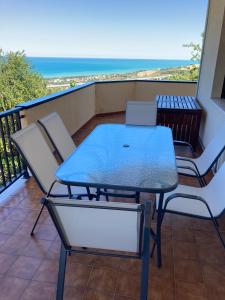 una mesa y sillas en un balcón con vistas al océano en La Foresteria- Azienda agricola Garra, en Mutignano