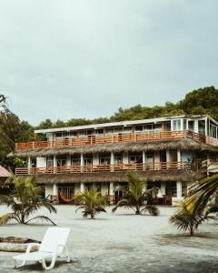 a building on the beach with a chair and palm trees at Casa Gaia: Un Paraiso in Mompiche