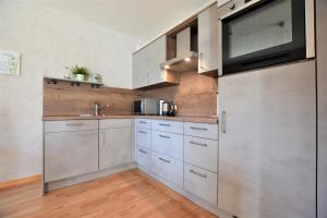 a kitchen with white cabinets and a flat screen tv at Haus Schwalbennest in Dahme