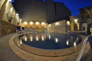 a swimming pool at night with chairs and a building at 6 Bedroom Farmhouse with Large Private Pool in Żebbuġ