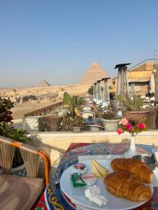 Queen cleopatra sphinx view في القاهرة: طبق من الطعام على طاولة مع الاهرامات في الخلفية