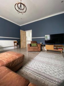a living room with a couch and a flat screen tv at The Cafe Apartment in Great Malvern
