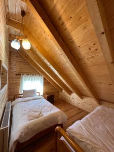 a bedroom with two beds in a wooden cabin at Shtepi Druri Arber in Voskopojë
