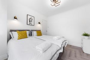 2 Betten in einem Schlafzimmer mit weißen und gelben Kissen in der Unterkunft 3 Bedroom House close to Dartford Station in Dartford