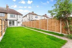 a backyard with a fence and green grass at 3 Bedroom House close to Dartford Station in Dartford