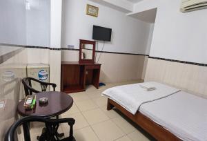 Zimmer mit einem Bett, einem Tisch und einem TV in der Unterkunft KHÁCH SẠN Như Ý in Ho-Chi-Minh-Stadt
