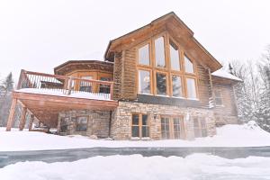 ein Haus im Schnee mit einer Terrasse in der Unterkunft Fiddler lake Resort Chalet 86 Deer in Mille-Isles