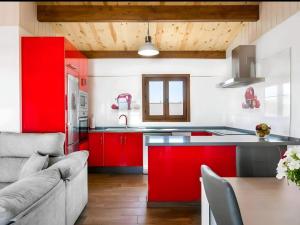 a kitchen with red cabinets and a couch at Bungalow para familias y parejas in Cádiz