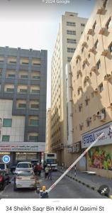 a street with cars parked in front of tall buildings at Fully furnished room in Sharjah