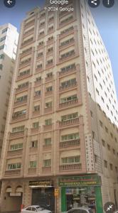 un edificio alto con coches estacionados frente a él en Fully furnished room en Sharjah