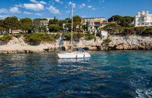 a white sailboat in the water in front of houses at LA MAISON DE DOMS vue mer in Cassis +57 photos