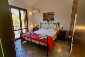 a bedroom with a bed with a red blanket on it at SanVitoTour- Residence Il Baglio in San Vito lo Capo