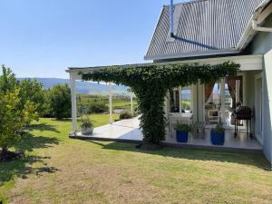 a white house with a pergola with plants at Katberg Mountain View House in Balfour