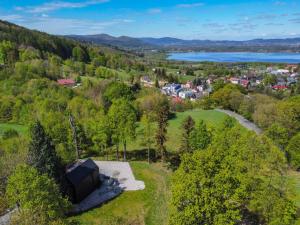 - une vue aérienne sur une petite maison située sur une colline à côté d'un lac dans l'établissement Domek PineHill z widokiem na Zalew by SpaceApart, à Sosnówka