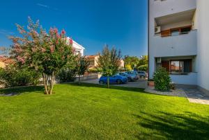 a green yard next to a building with cars parked at Apartments Kvarner 2 in Malinska