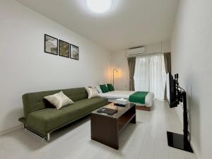 a living room with a green couch and a bed at Neighbor's Hotel 楽々園 in Hiroshima