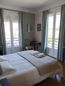 een slaapkamer met een groot wit bed en ramen bij Villa Saint-Germain in Saint-Georges-de-Didonne