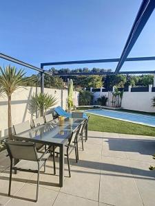 einen Tisch und Stühle auf einer Terrasse neben einem Pool in der Unterkunft Villa T4 avec Piscine et cuisine d'été in La Seyne-sur-Mer