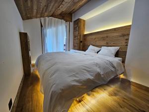 a bedroom with a large bed with a wooden wall at Magnifique attique avec vue sur le lac de la Moubra in Crans-Montana