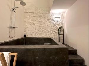 a large bath tub in a room with a stone wall at Rustic Style Apartments & Studios BCN in Barcelona
