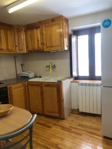 cocina con armarios de madera, mesa y nevera en Apartamento Forn de Serra, en Lladorre