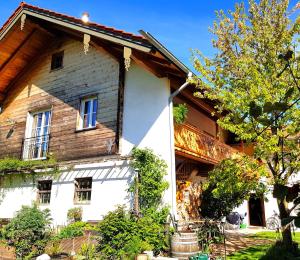 ein altes Holzhaus mit einem Baum davor in der Unterkunft Ferienwohnung Schreiner-Viehhausen in Grassau