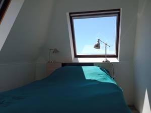 um quarto com uma cama azul e uma janela em Appartement 45m2 - Proche Deauville - Vue Mer em Bénerville-sur-Mer