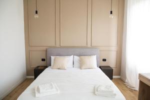 a bedroom with a white bed with two towels on it at Casa Enea - Luxury House Milano Navigli in Milan
