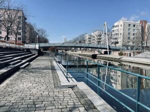 a walkway next to a river with a bridge at Ruoholahti Apartment with private sauna in Helsinki