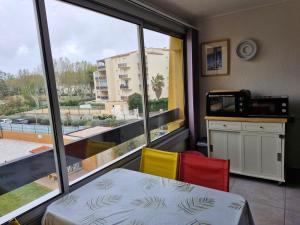 Zimmer mit einem Tisch und Stühlen sowie einem großen Fenster in der Unterkunft Sopraland T3 45m2 à 300m plage Richelieu in Cap d'Agde