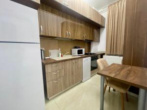 cocina con armarios de madera, mesa y nevera en Central Adress DD14, en Bucarest
