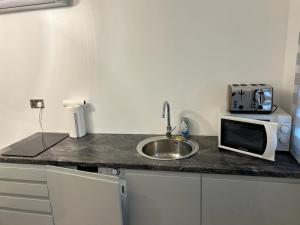 a kitchen counter with a sink and a microwave at Ana guest house in Hookwood