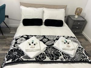 a bed with a black and white comforter and towels on it at Ana guest house in Hookwood