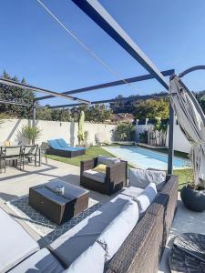 eine Terrasse mit einem Sofa, einem Tisch und einem Pool in der Unterkunft Villa T4 avec Piscine et cuisine d'été in La Seyne-sur-Mer