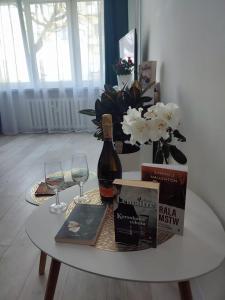 a table with a bottle of wine and a vase of flowers at Kawalerka apartament ul gieldowa in Kołobrzeg