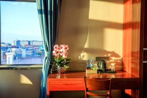 a desk with a vase of flowers and a window at Notis International Hotel 诺蒂斯国际酒店 in Phnom Penh