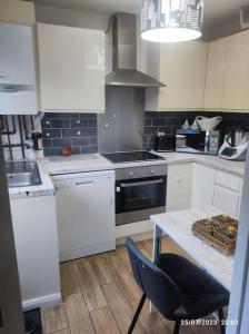 a kitchen with white cabinets and a table and a stove at Cosy house close to London Bridge in London