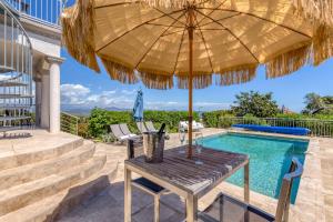 Stunning Cote d'Azur Villa - Rives d'Or في فريجوس: طاولة مع مظلة بجانب مسبح