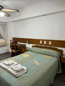 Un dormitorio con una cama verde con toallas. en Hotel y Restaurant Don Quijote en Macachín