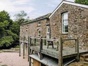 a wooden bridge in front of a stone building at The Old Mill in Hackthorpe