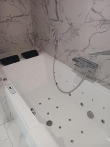 bañera blanca con manguera en el baño en Touraco, en Villars-les-Dombes