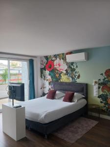 1 dormitorio con 1 cama grande y pared de flores en Touraco, en Villars-les-Dombes
