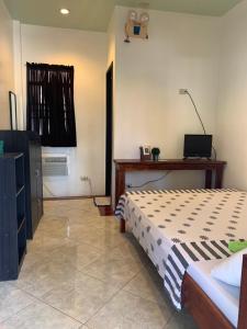 um quarto com uma cama, uma mesa e uma televisão em LS Garden Villa em Puerto Princesa