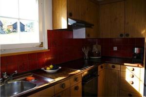 cocina con armarios de madera, fregadero y ventana en Tanzhus en Wildhaus