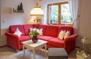 a red couch in a living room with a table at Ferienwohnung in Walkenried mit Gepflegtem Garten in Walkenried
