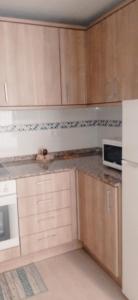 a kitchen with wooden cabinets and a white refrigerator at Bonito bajo cerca del mar in Benicarló